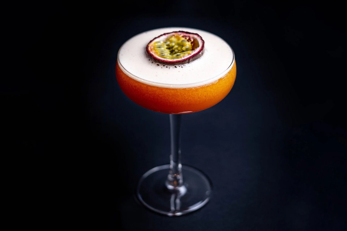TikTok MockTini — alcohol-free passion fruit mocktail in a coupe glass, topped with foam and a passion fruit half